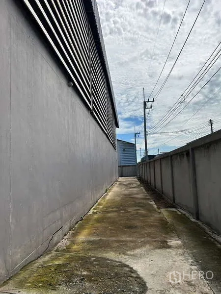 货栈 出售在Lat Lum Kaeo, Pathum Thani - 仓库一侧的服务通道，围墙、电线与门禁出入口。