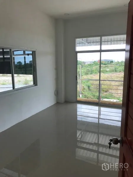 Warehouse for rent in Samut Sakhon - Bright office room with glossy tiled floor, sliding glass door to a balcony and side window.