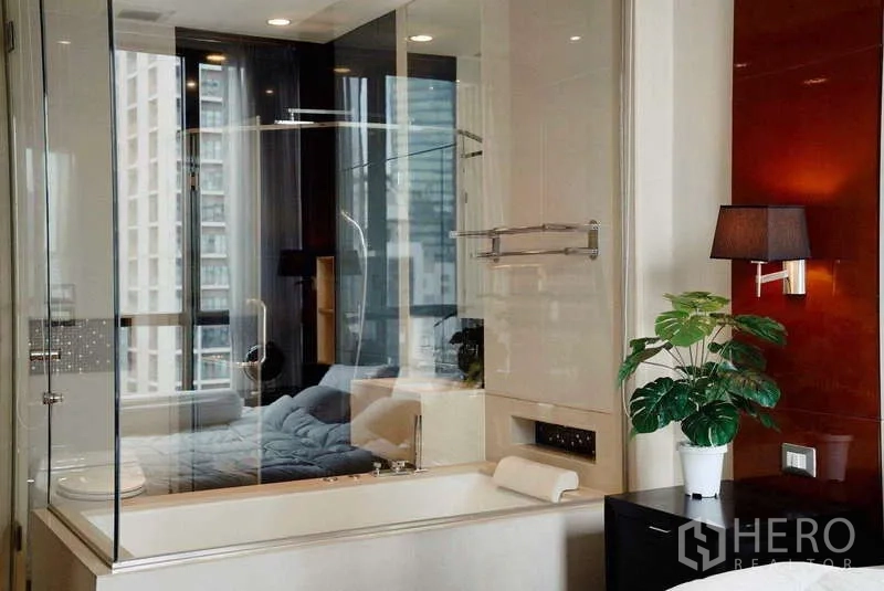 Condominium for rent or sale - Bathroom tub and shower separated by glass, with bedroom and city view beyond.