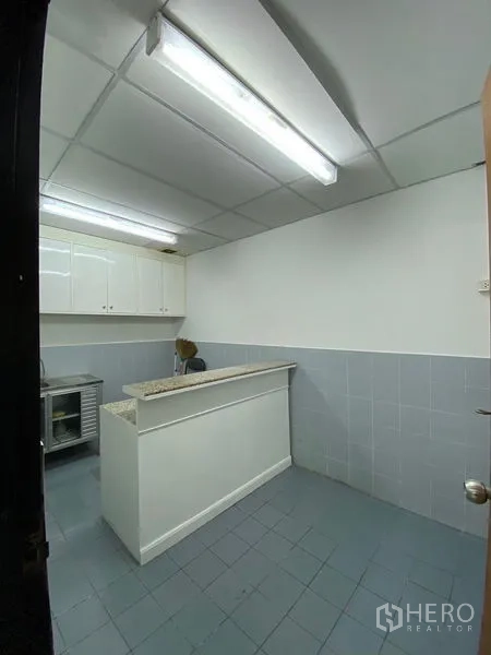 Office Space for rent - Compact office pantry with countertop, overhead cabinets and tiled flooring.