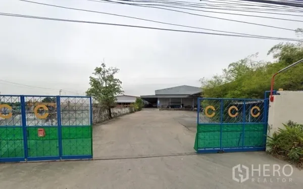 คลังสินค้า ให้เช่าในBang Phli, Samut Prakan - ทางเข้าโกดังพร้อมประตูรั้วและลานคอนกรีตกว้าง อาคารหลังคาเมทัลชีทด้านใน บางพลี สมุทรปราการ