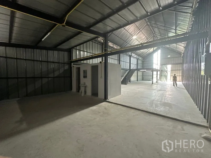 Warehouse for rent in Bueng Kum, Bangkok - Open plan storage area with a restroom corner and long clear span leading to the front loading door.