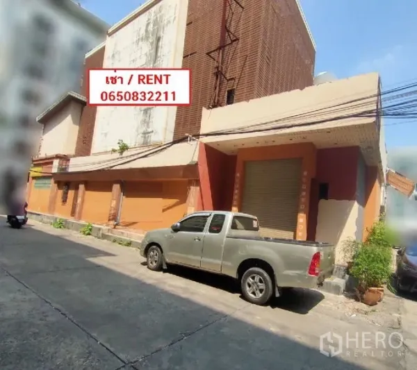 Retail Space for rent in Watthana, Bangkok - Street-facing commercial building with roller shutter entrance and a pickup truck parked outside.