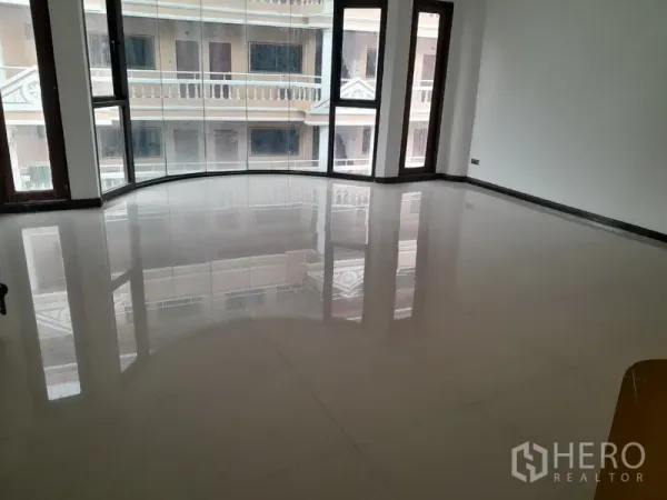 联排别墅 出租在Khlong Toei, Bangkok - 宽敞客厅，亮面白色地砖与弧形落地窗，采光充足