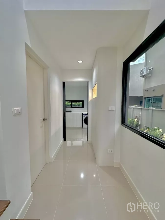 独立式住宅 出租或出售在Prawet, Bangkok - 走廊通往厨房，侧窗采光与亮面地砖。