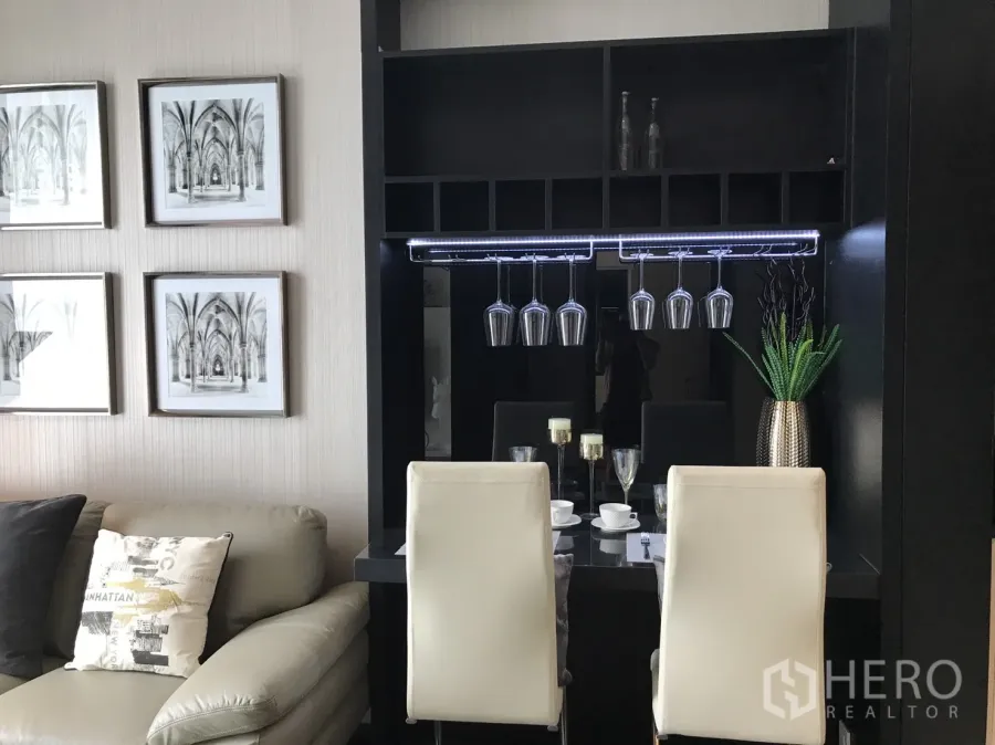 公寓 出租或出售在Watthana, Bangkok - 公寓客厅内的餐吧，酒杯吊架、白色餐椅与墙面装饰画