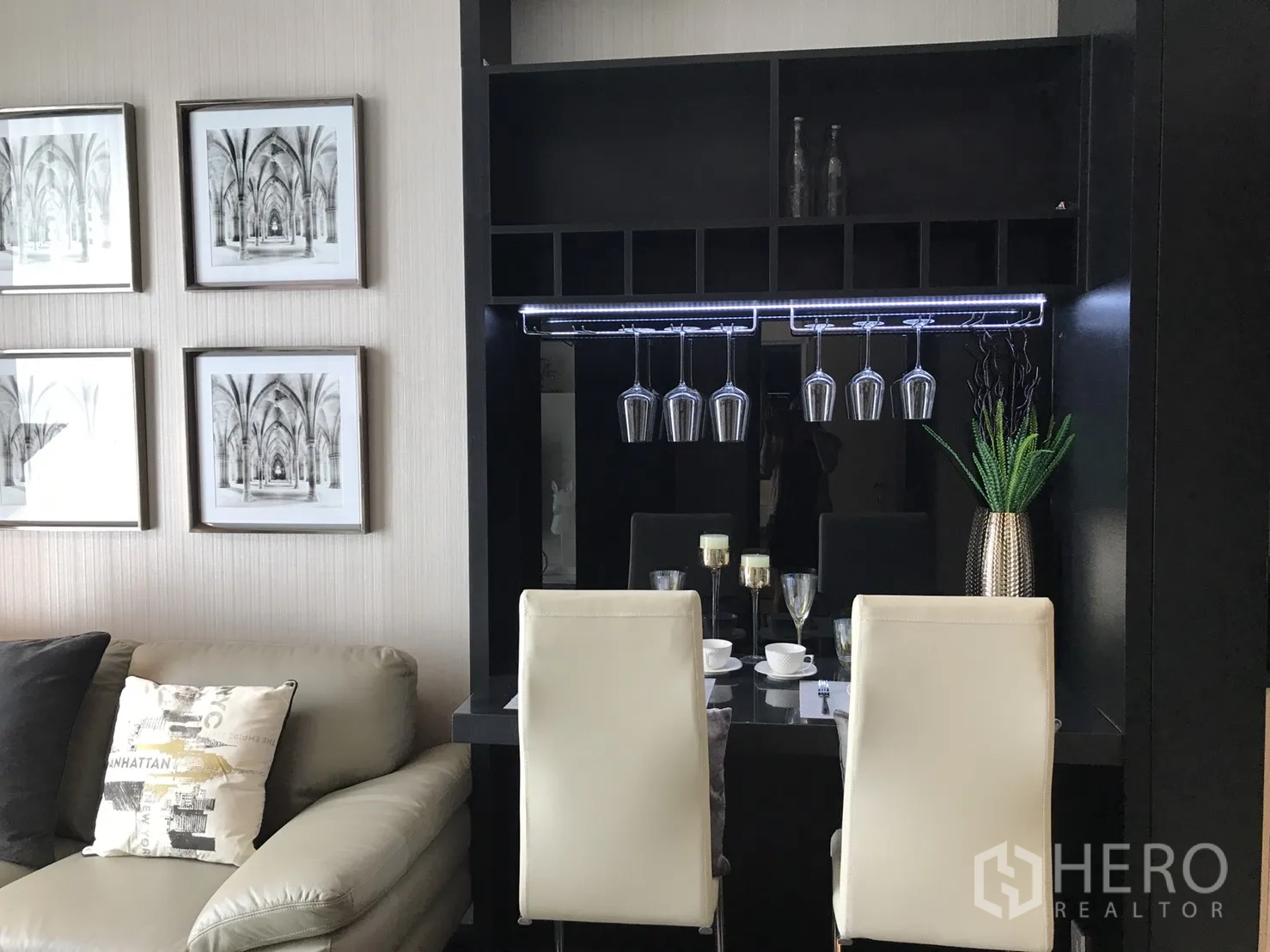 公寓 出租或出售在Watthana, Bangkok - 公寓客厅内的餐吧，酒杯吊架、白色餐椅与墙面装饰画