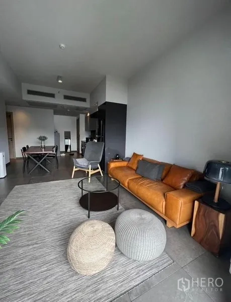 公寓 出租在Watthana, Bangkok - 客餐厅一体空间，沙发与坐墩，望向厨房与玄关