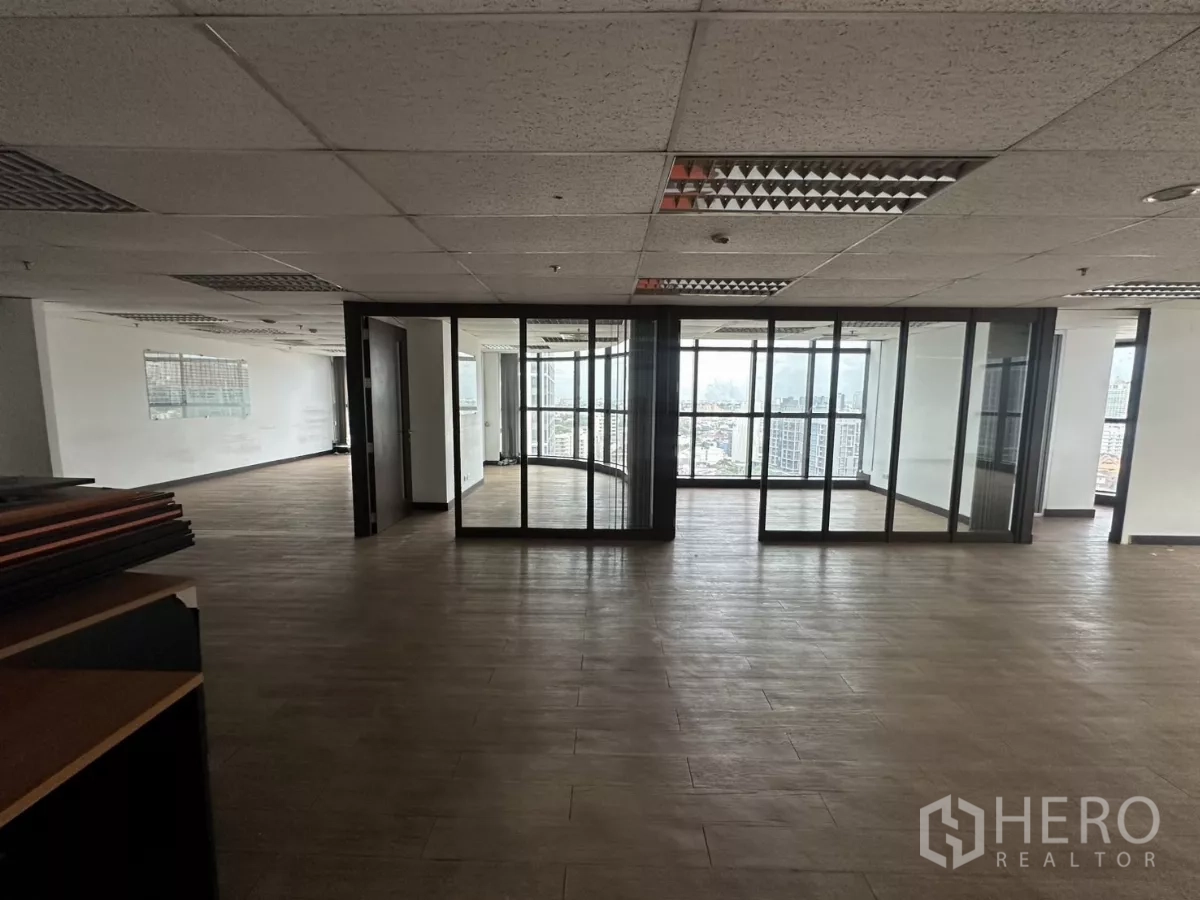 办公空间 出租在Watthana, Bangkok - 中央区域以玻璃隔断形成私密房间，配有全景窗与城市景致。