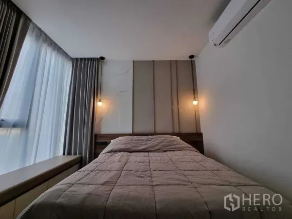 Condominium for rent in Ratchathewi, Bangkok - Cozy bedroom with padded headboard, pendant lights and sheer curtains.