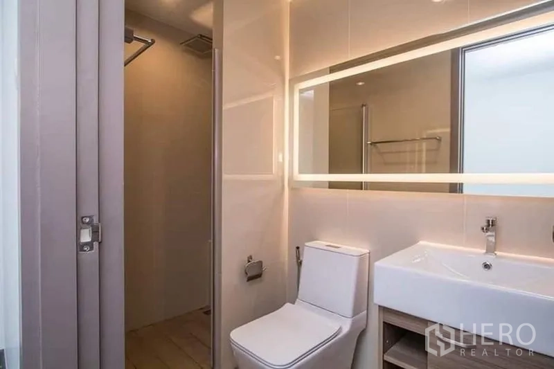 Home Office for rent in Don Mueang, Bangkok - Contemporary bathroom with illuminated mirror, vanity, toilet and separate shower area.