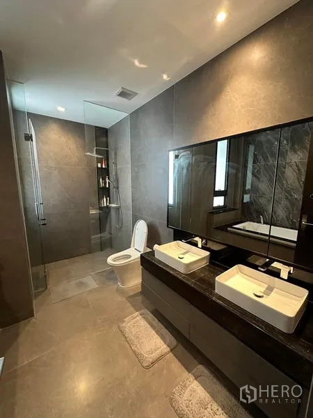 Detached House for rent in Saphan Sung, Bangkok - Primary bathroom with double vanity, glass shower and warm lighting.
