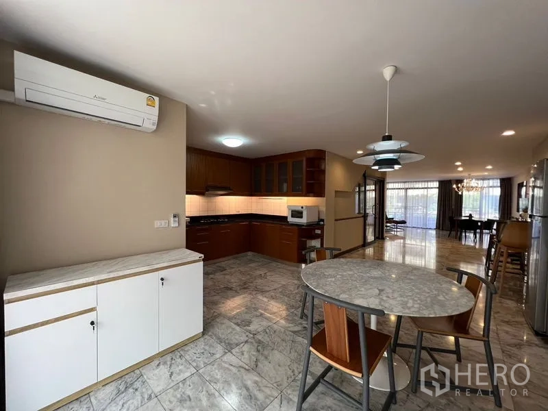 Townhouse for rent or sale in Suan Luang, Bangkok - Eat-in kitchen with marble floors, wood cabinetry and a round dining table.