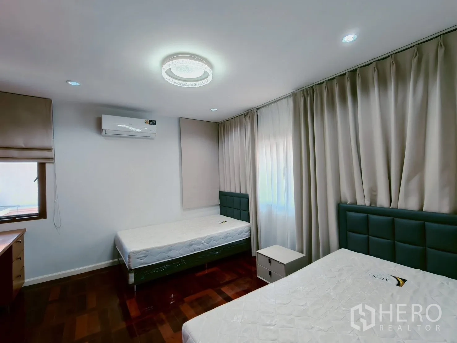 Detached House for rent in Lat Krabang, Bangkok - Guest room with two single beds, heavy drapes, ceiling light and polished wood floor.