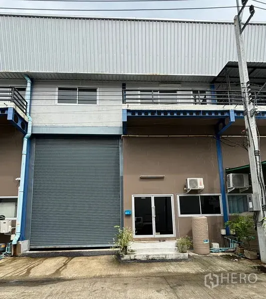 Warehouse for rent in Krathum Baen, Samut Sakhon - Warehouse exterior with high roller shutter, glass office entrance and balcony railings in Krathum Baen.