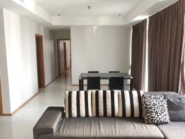公寓 出租在Khlong Toei, Bangkok - 宽敞起居区，条纹靠垫沙发，四人餐桌，走廊通往卧室。