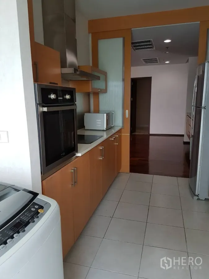 公寓 出租或出售在Watthana, Bangkok - 走廊式厨房，嵌入式烤箱、抽油烟机、木质橱柜与洗衣机