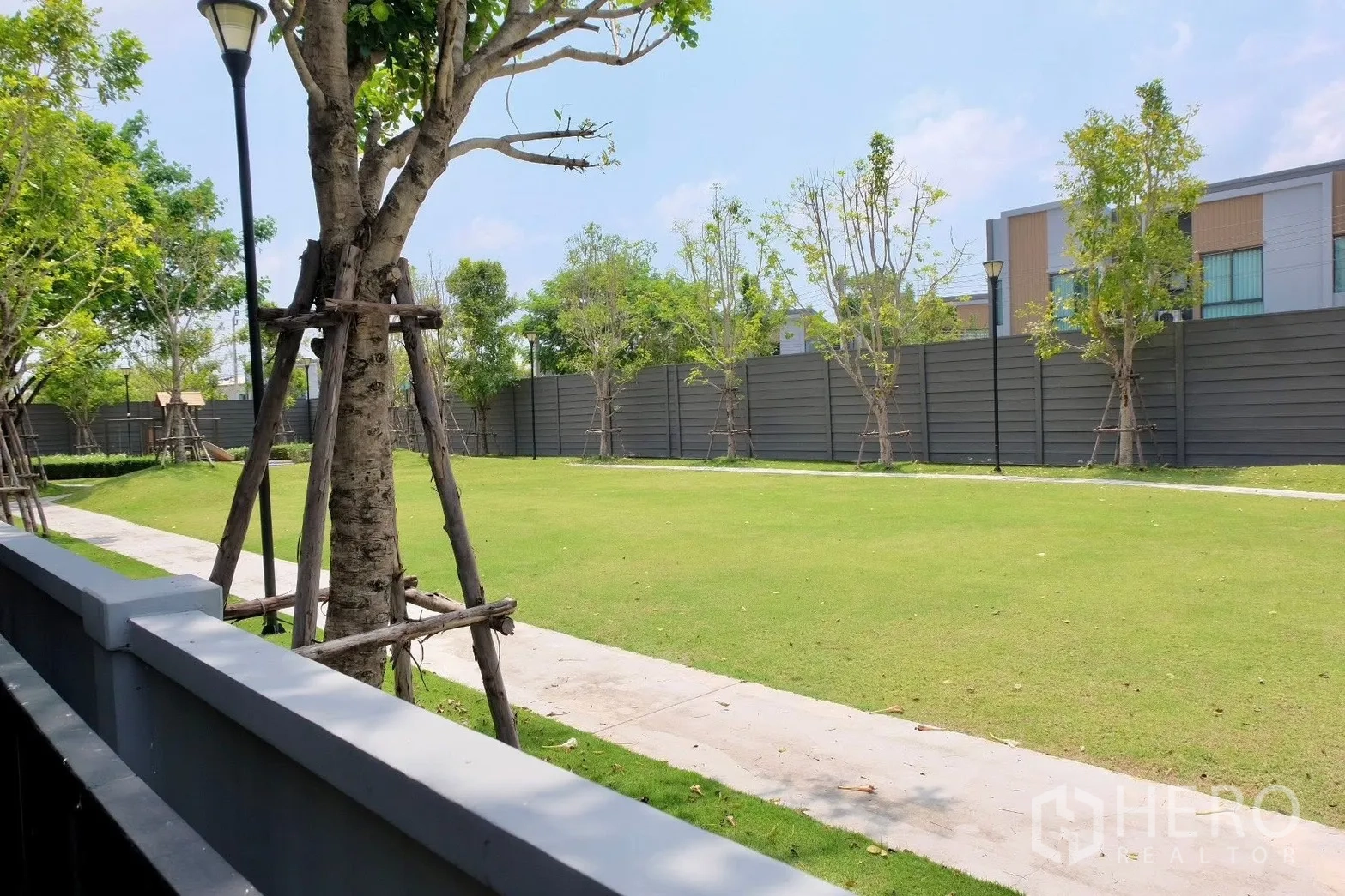 半独立式住宅 for sale in Prawet, Bangkok - 公共草坪配人行道与树木围栏的景观花园。