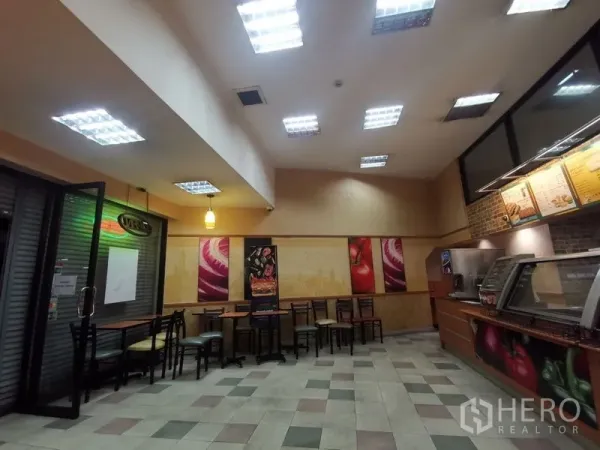 Shophouse for rent in Bangkok - Dining area with tables and chairs under recessed lighting next to a glass entry.