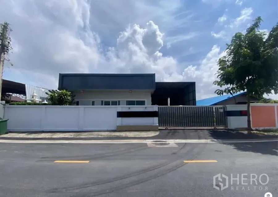 Warehouse for sale in Mueang Samut Prakan, Samut Prakan - Modern office frontage and sliding gate of the warehouse complex along a tidy street.