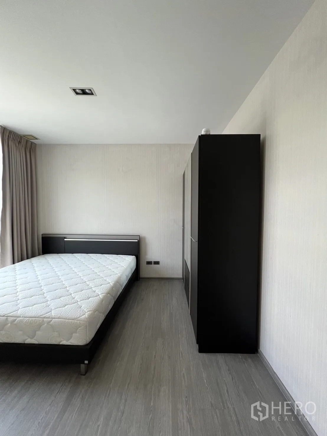 Townhouse for rent in Lat Phrao, Bangkok - Bedroom angle showing bed frame and full-height wardrobe against light walls.