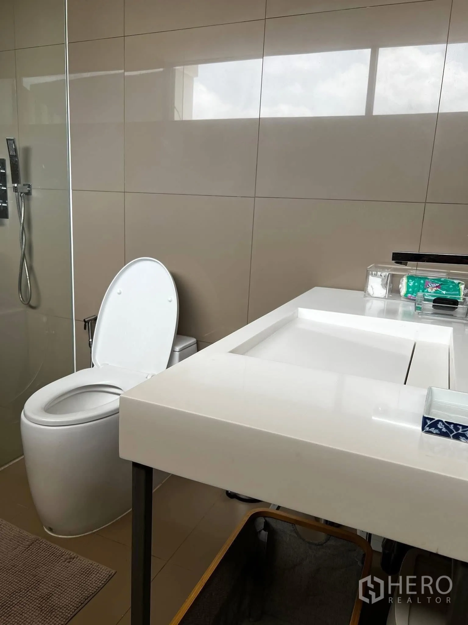 联排别墅 for rent or sale in Watthana, Bangkok - 卫浴内白色台盆柜，旁设玻璃淋浴间与坐便器。