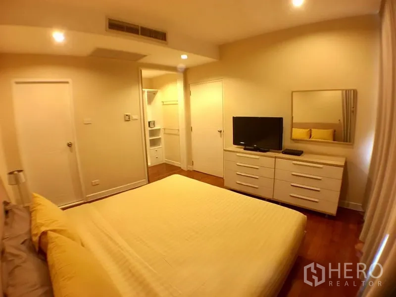 Condominium for rent in Khlong Toei, Bangkok - Cozy bedroom with king bed, dresser and TV, wood floors and walk-in closet access.
