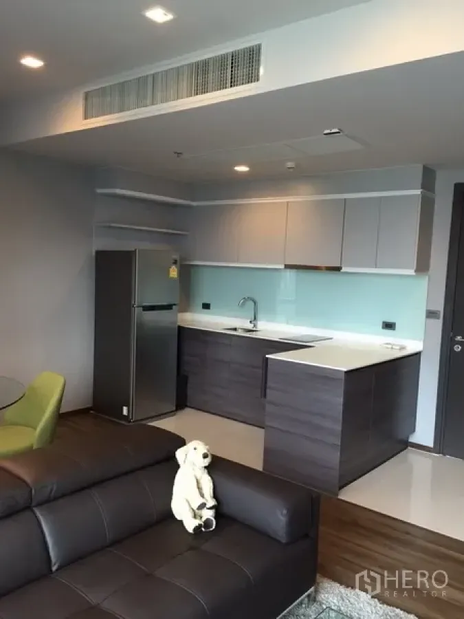 Condominium for rent in Watthana, Bangkok - Modern open-plan kitchen with glossy cabinets, glass backsplash, and full-size fridge in a Bangkok condo.