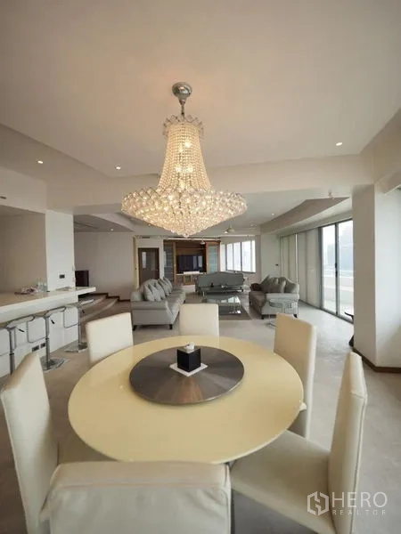 Condominium for rent in Khlong San, Bangkok - Open-plan lounge and dining space with statement chandelier and sliding glass doors.
