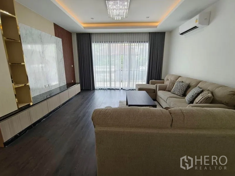 独立式住宅 出租或出售 - 客厅配沙发、仿石纹电视墙、水晶吊灯与阳台推拉门。
