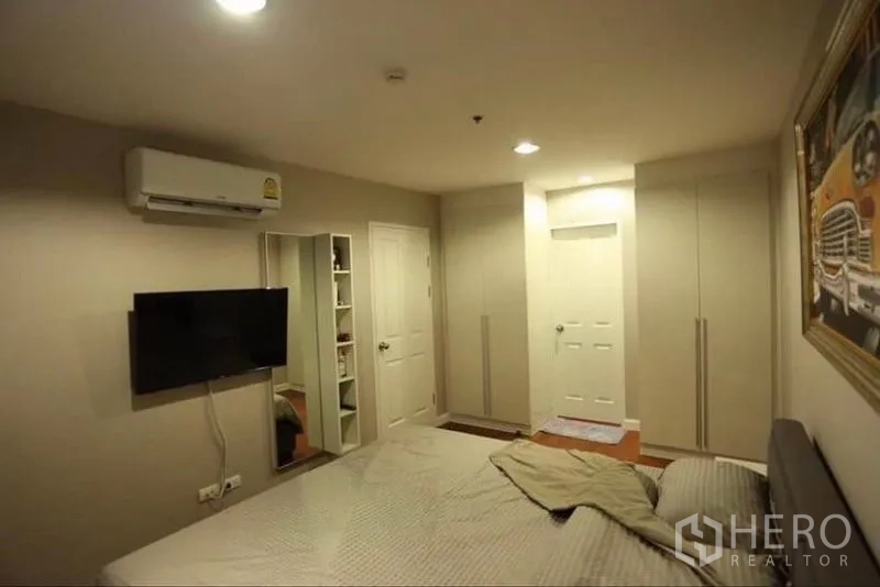 คอนโด ให้เช่าในHuai Khwang, Bangkok - ห้องนอนใหญ่พร้อมทีวีติดผนัง ตู้เสื้อผ้า แอร์ และโทนสีอบอุ่น