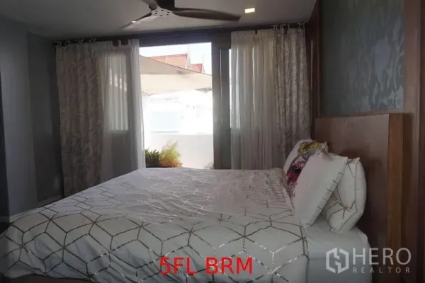 Shophouse for sale in Phra Khanong, Bangkok - Bedroom with a large bed, ceiling fan and curtains, opening to a small terrace.