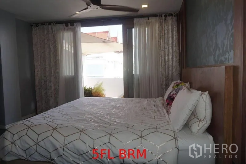Shophouse for sale in Phra Khanong, Bangkok - Bedroom with a large bed, ceiling fan and curtains, opening to a small terrace.