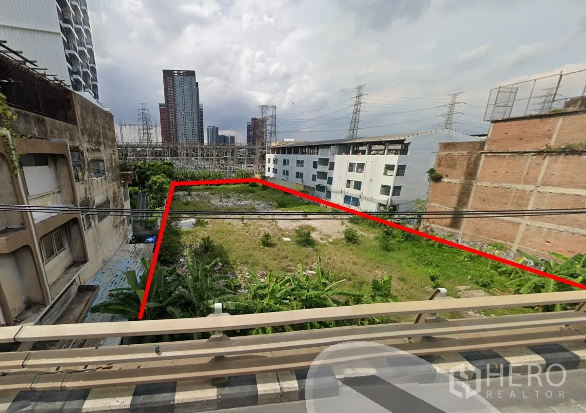 Land for sale in Suan Luang, Bangkok - Aerial view showing the rectangular plot outlined in red between neighboring buildings and city towers.