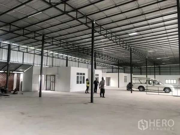 Warehouse for rent in Pathum Thani - Interior view showing built-in office rooms beneath a steel roof inside the warehouse.
