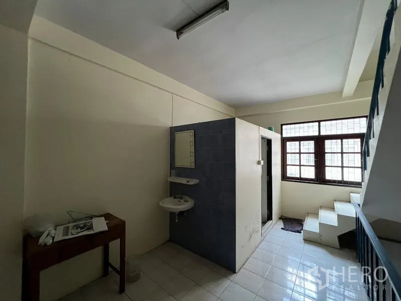 Shophouse for sale in Phra Khanong, Bangkok - Upper floor landing with built‑in bathroom cubicle, sink and stairway.