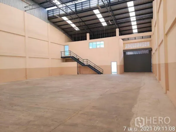 Factory for rent in Bang Bua Thong, Nonthaburi - Spacious warehouse interior with high steel roof, skylights, mezzanine office and shutter.