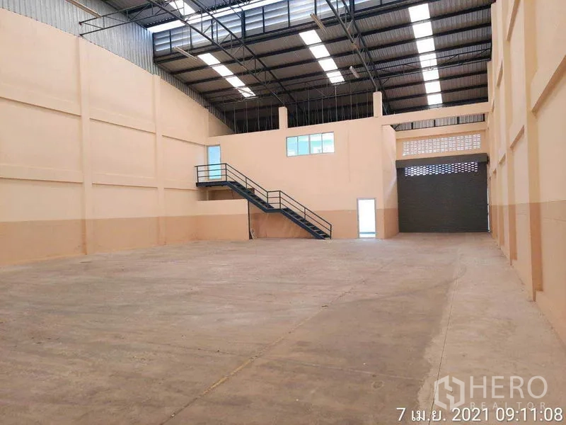 Factory for rent in Bang Bua Thong, Nonthaburi - Spacious warehouse interior with high steel roof, skylights, mezzanine office and shutter.