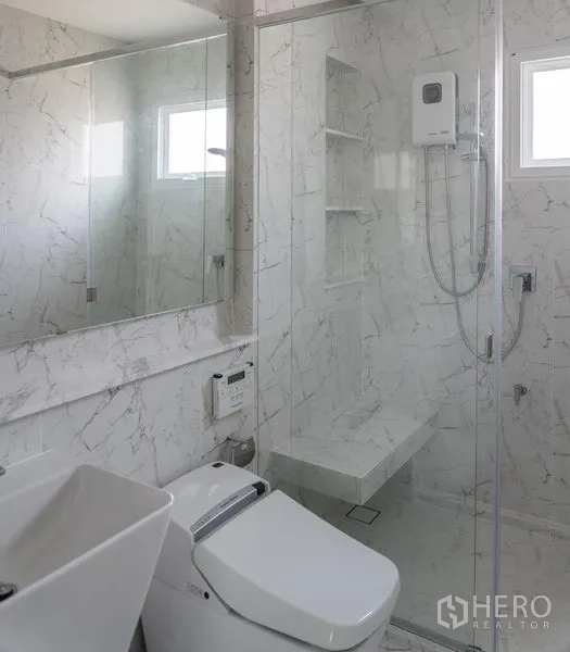 Detached House for rent in Samut Prakan - Marble-tiled bathroom with glass shower enclosure, vanity and smart toilet.
