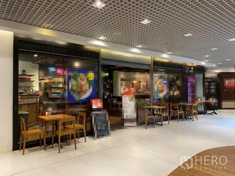 พื้นที่ขายปลีก ให้เช่าในKhlong Toei, Bangkok - หน้าร้านค้าภายในศูนย์การค้า กระจกบานใหญ่ ไฟอบอุ่น และโต๊ะนั่งสไตล์คาเฟ่
