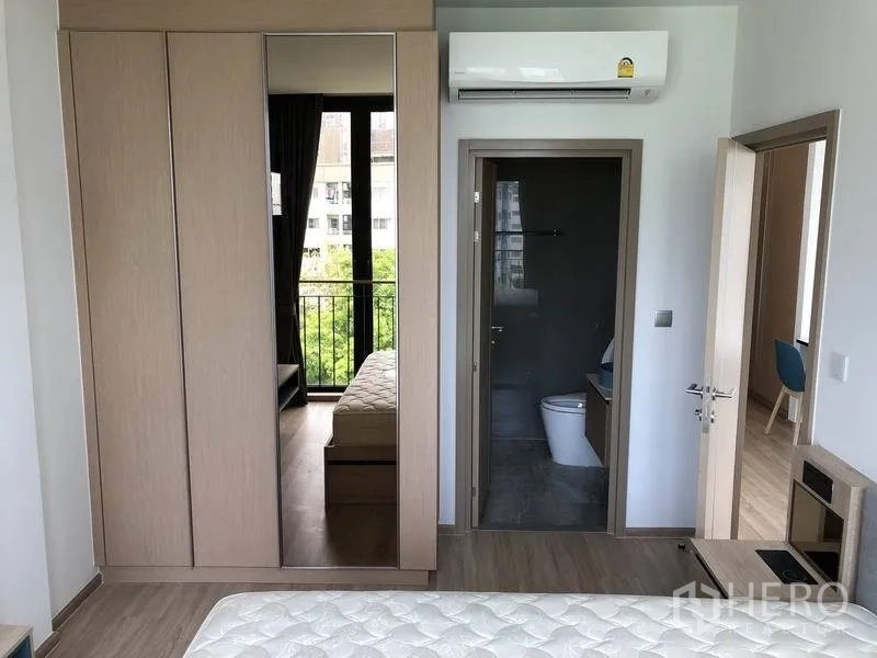 公寓 出租在Watthana, Bangkok - 主卧带镜面衣柜、空调，并连接套间浴室入口。
