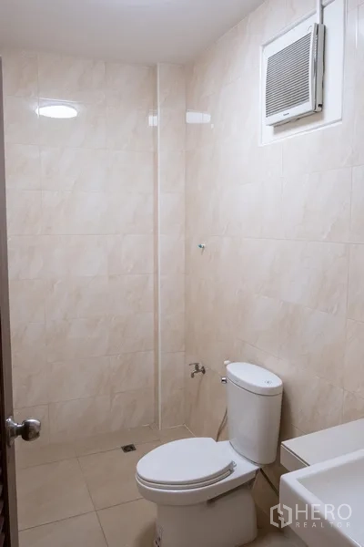 Home Office for rent in Khlong Toei, Bangkok - Bathroom with beige tiles, toilet and shower area.