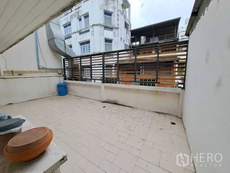 Shophouse for rent in Watthana, Bangkok - Open tiled terrace with privacy screen and urban backdrop.