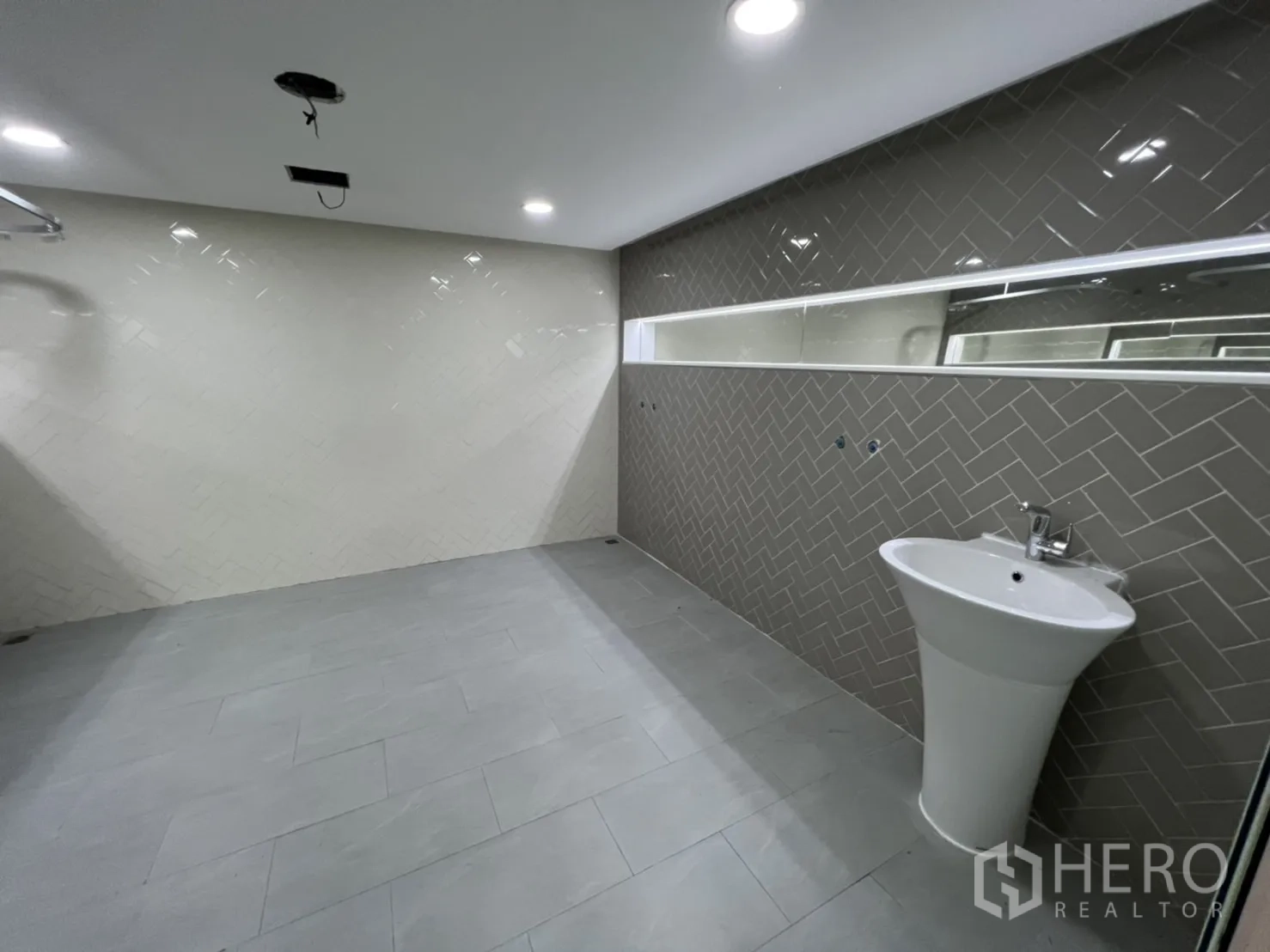 Shophouse for rent or sale in Watthana, Bangkok - Large tiled bathroom with a long mirror and pedestal sink.