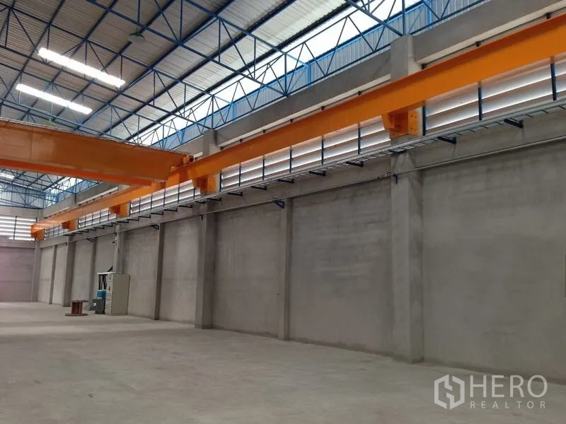 货栈 出租在Mueang Samut Prakan, Samut Prakan - 起重机跑道梁与实体混凝土墙的近景，配百叶通风窗与电力设备。