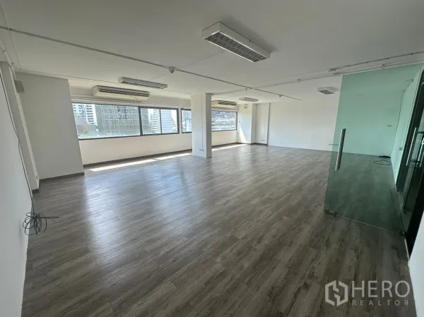 办公空间 出租 - 无家具办公室内景，整排窗户、分体空调与吊顶荧光灯。