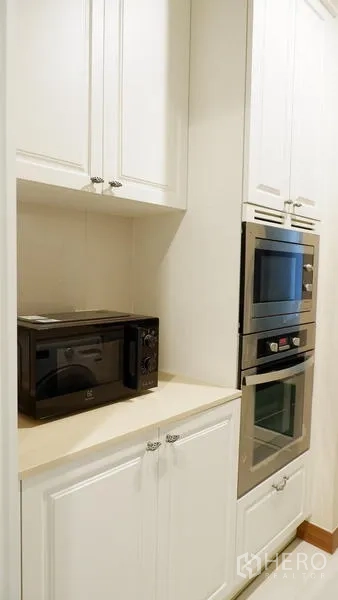 Condominium for rent in Watthana, Bangkok - Built-in microwave and double ovens integrated into white kitchen cabinets.
