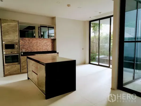 Detached House for sale in Wang Thonglang, Bangkok - Modern kitchen with island, built-in oven and microwave, and sliding doors to the garden.