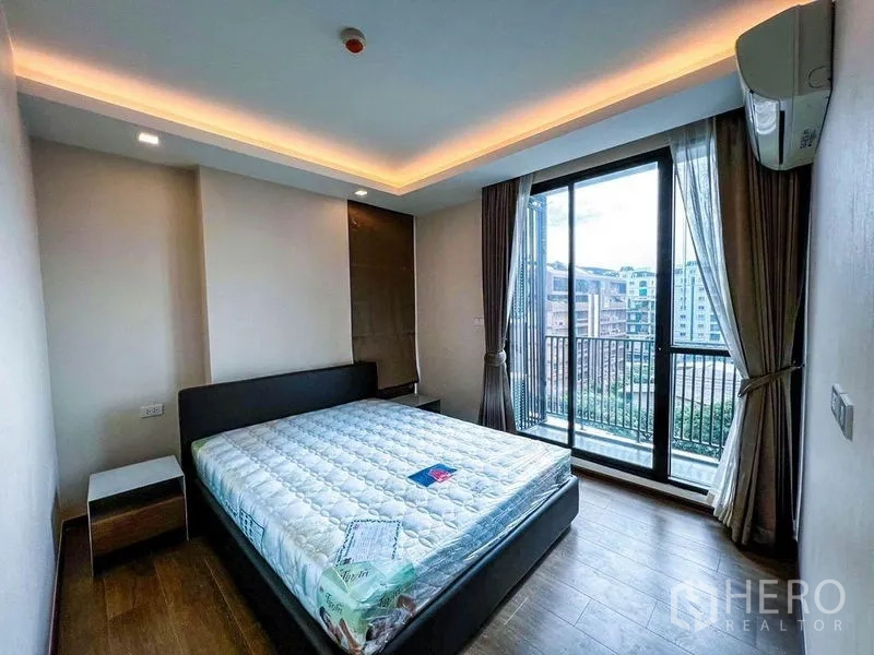 คอนโด ขายในHuai Khwang, Bangkok - ห้องนอนมาสเตอร์ ไฟฝ้าซ่อน ผนังกระจกสูงจรดเพดาน เปิดออกสู่ระเบียงพร้อมวิวเมือง