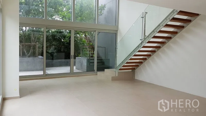 公寓 出售在Khlong San, Bangkok - 挑高客厅与悬浮木梯，面向花园玻璃墙
